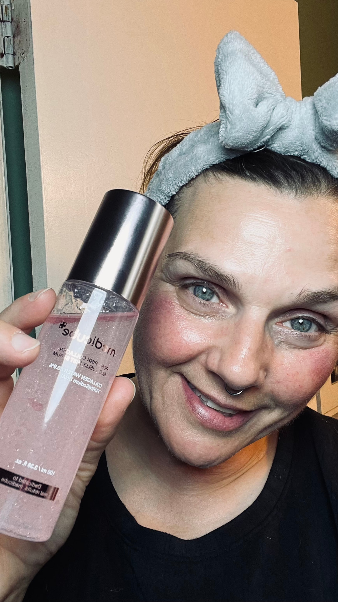 Candice holding a pink collagen mist serum on camera